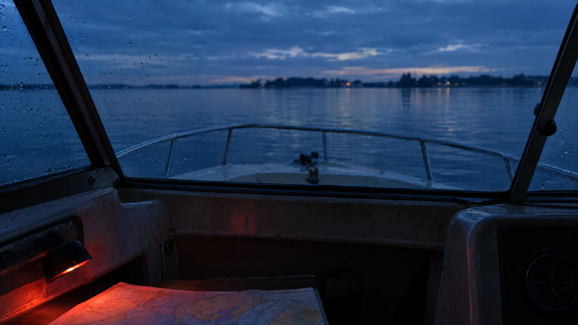 Blick aus einem Bootscockpit aufs Wasser in der Dämmerung, unten eine rot beleuchtete Karte