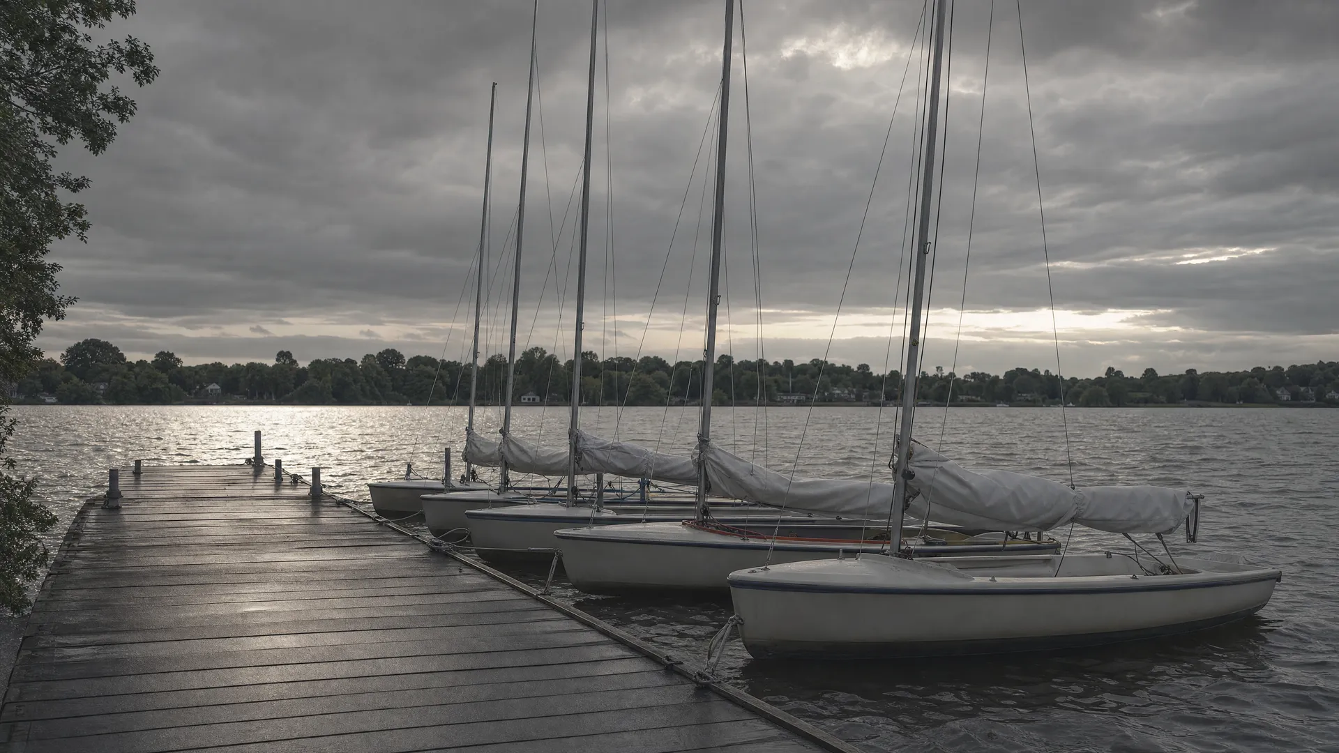 Jollen mit aufgetuchten Segeln am Steg eines Segelvereins am Abend