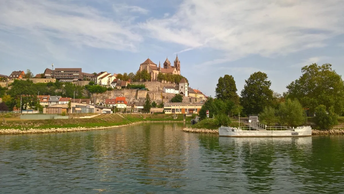 Blick vom Wasser auf Breisach am Rhein mit dem St.-Stephans-Münster auf dem Münsterberg, rechts eine weiße Anlegeplattform am Ufer