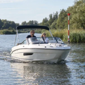 Sportboot auf einem Fluss mit Schilf und Fahrwassertonne