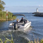 Sportboot fährt aus einer Flussmündung auf die Ostsee